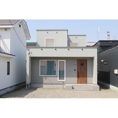 グレーの外壁と木目調のドアで、落ち着いた印象です